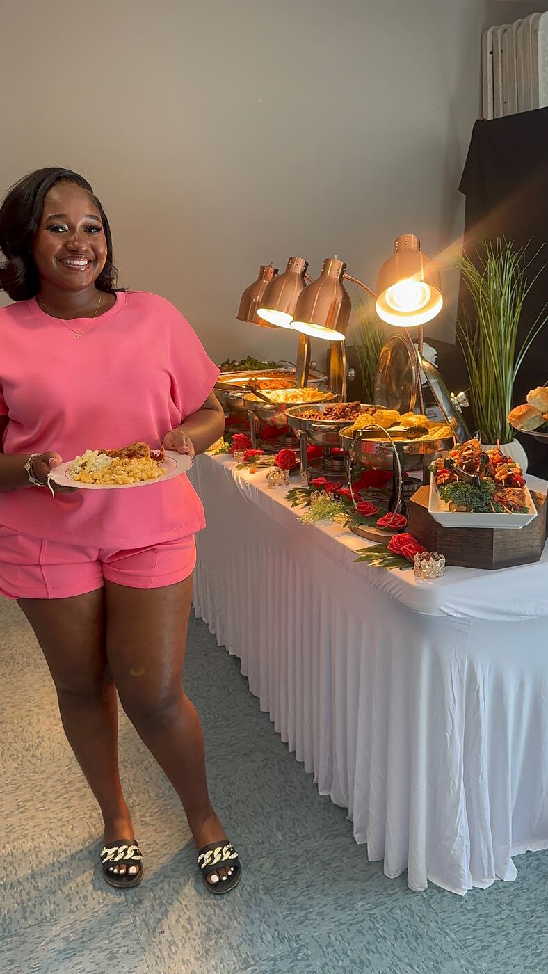 Smiling guest in pink holding her plate at a catered buffet