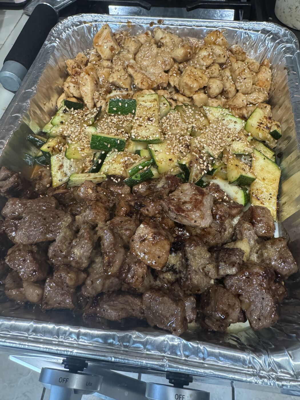 Hibachi tray of steak, chicken and zucchini finished with sesame